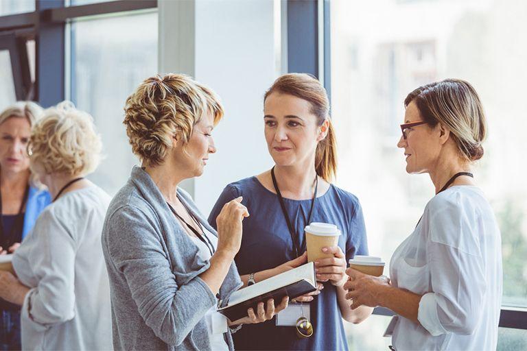 Three women network during a break at a conference.