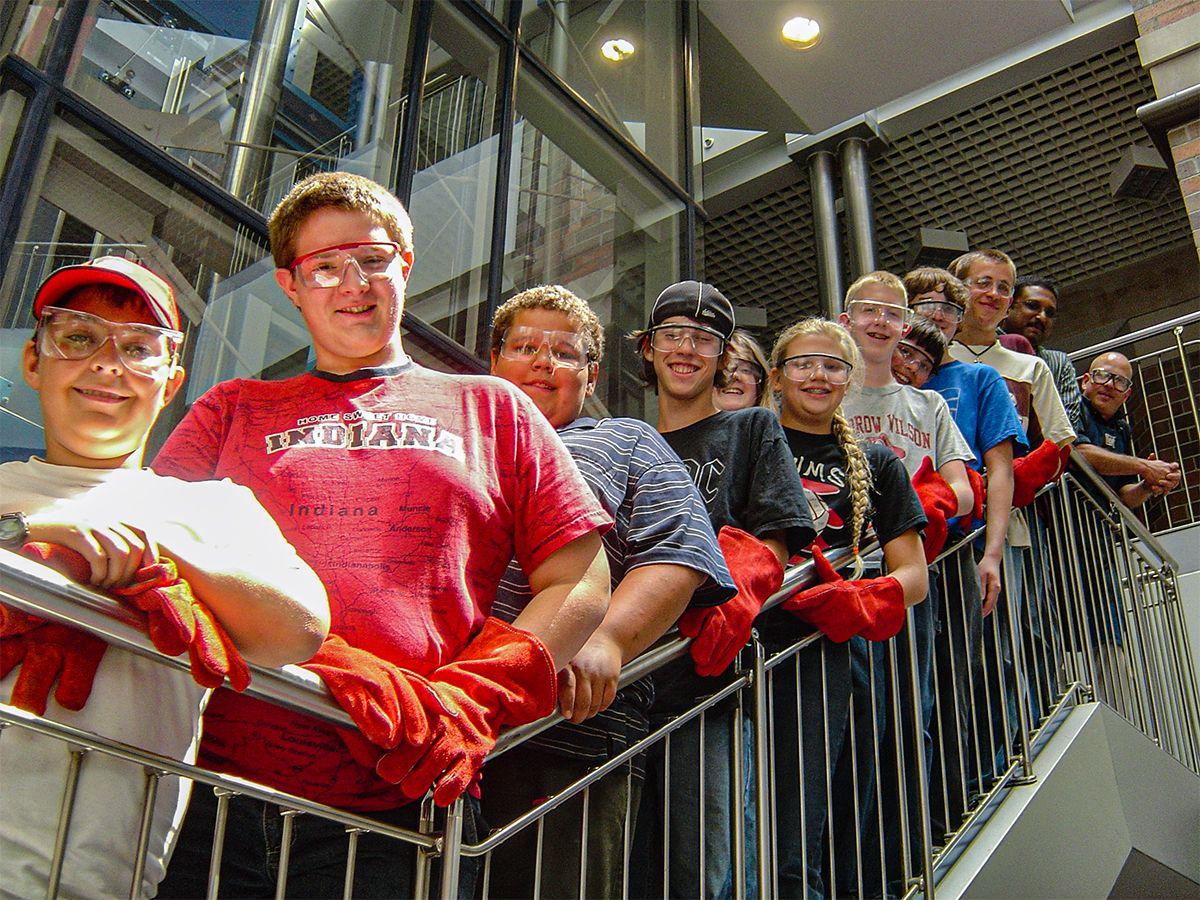 Group of campers posing on stairs wearing welding gloves
